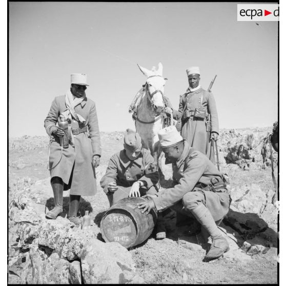 Lors d'une halte, des tirailleurs de la 10e compagnie du 3e bataillon du 17e RTS ouvrent un tonneau.