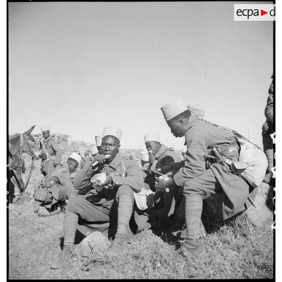 Lors d'une halte, des tirailleurs du 17e RTS mangent.