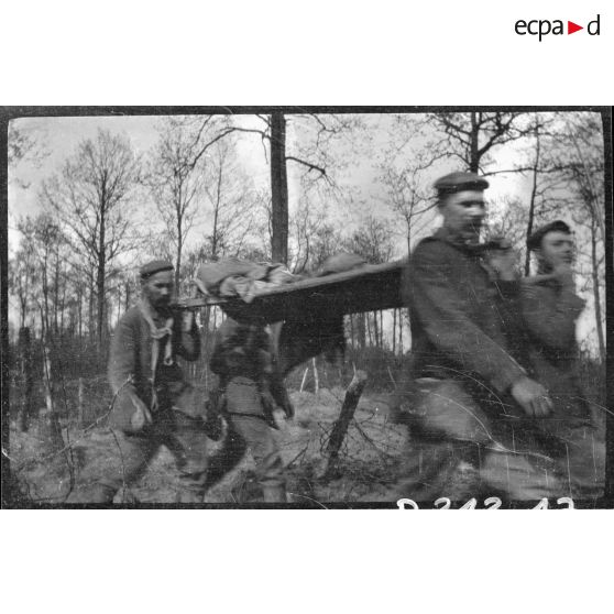 [Des soldats transportent un blessé sur un brancard].