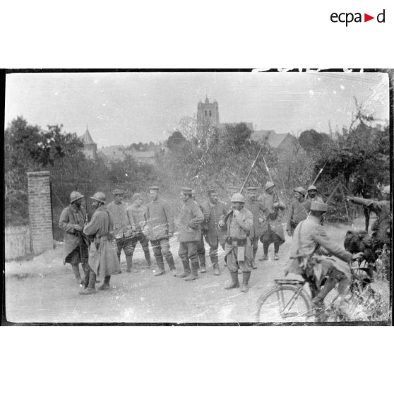 [Un groupe de soldats et de prisonniers devant un village].