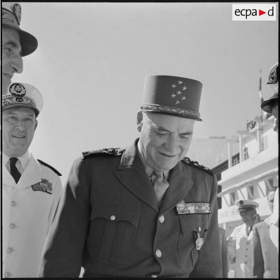 Portrait du maréchal Juin à l'aéroport d'Alger accompagné d'une délégation composée du général Cailles.