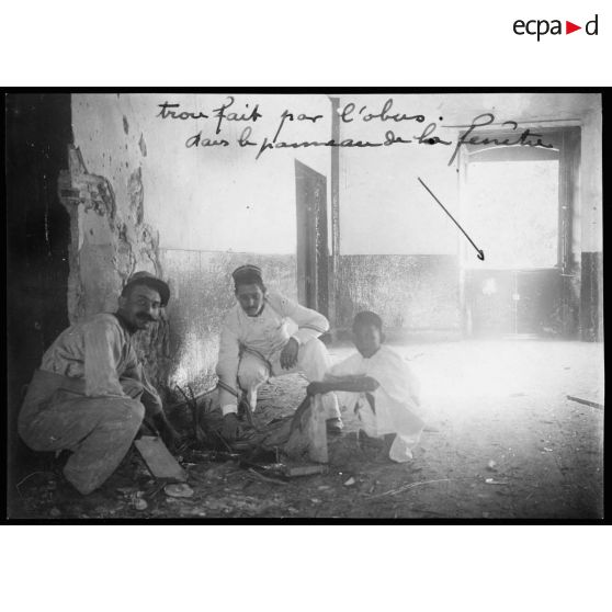 Photo prise à 8h du matin dans la manutention. Salle des farines. Un obus est entré de la fenêtre et a pénétré dans le parquet à une distance d'environ 7 ou 8 mètres de la fenêtre.  Ce qui prouve que la trajectoire en était extrémement faible et que pour venir du Breslau, l'obus a dû passer devant le 1er étage de la maison de la Place, soit en frôlant le toit de la véranda, soit même en filant dans la véranda car le bateau allemand était exactement dans la direction de la véranda. Me trouvant sur cette véranda, je voyais à droite la manutention et à gauche, exactement le Breslau. La chambre des farines en bas a été plus abîmée.  [légende d'origine]