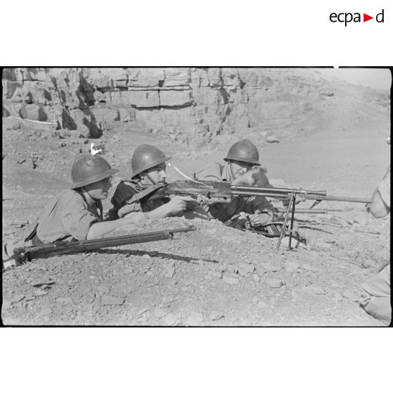 Trois jeunes engagés militaires s'entraînenet au tir, dans une zone montagneuse.