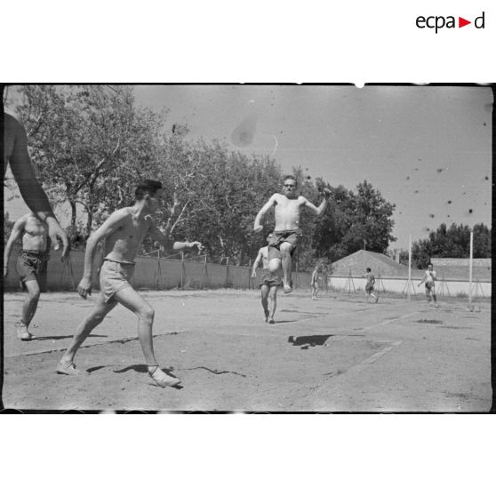 Des jeunes engagés militaires s'entraînent au saut en longueur en plein air.