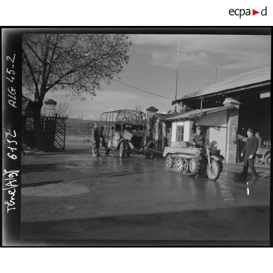 Un camion est amené à la chaîne, remorqué par un véhicule léger motorisé Ketten-Krad NSU HK 101 (chenillette).