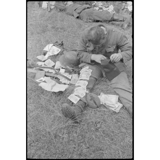 Après avoir échappé à la retraite de Vilnius, un fantassin allemand fait sécher le contenu de ses poches, ici, des billets de banque.