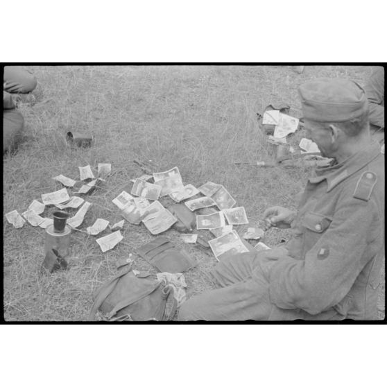 Après avoir échappé à la retraite de Vilnius, un fantassin allemand fait sécher le contenu de ses poches, ici, des billets de banque.