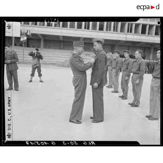 Remise de décoration à un jeune diplômé du brevet à la préparation militaire par un général de division au stade Leclerc d'Alger.
