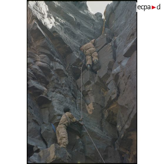 Formation des aides moniteurs commando et des élèves officiers de l'école militaire interarmes d'Atar à l'escalade et au rappel, aux techniques de cordes et d'assurance, au franchissement de fortune, au brancardage dans les falaises de l'Oued Illïj, région d'Atar et d'Azougui. Température d'exercice avoisisant les 40° en raison du rayonnement sur les parois rocheuses, 300 élèves et 10 aides moniteurs ont été formés pendant cette période. [légende d'origine]<br>