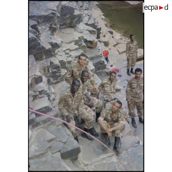 Formation des aides moniteurs commando et des élèves officiers de l'école militaire interarmes d'Atar à l'escalade et au rappel, aux techniques de cordes et d'assurance, au franchissement de fortune, au brancardage dans les falaises de l'Oued Illïj, région d'Atar et d'Azougui. Température d'exercice avoisisant les 40° en raison du rayonnement sur les parois rocheuses, 300 élèves et 10 aides moniteurs ont été formés pendant cette période. [légende d'origine]<br>