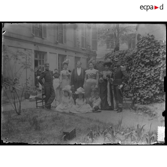 [Portrait de groupe de famille dans un jardin avec deux militaires en uniforme].<br>