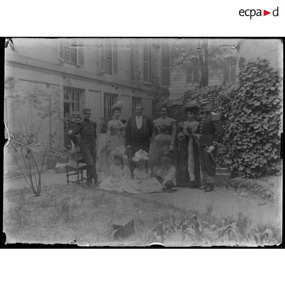 [Portrait de groupe de famille dans un jardin avec deux militaires en uniforme].<br>