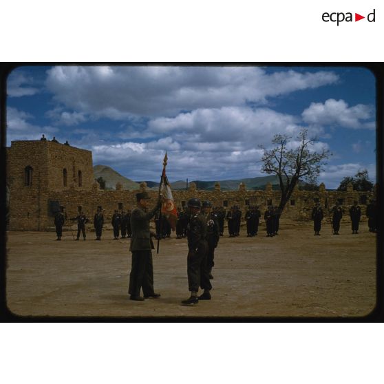 Passage de commandement : le colonel Deluc remet l'étendard au général. [légende d'origine]