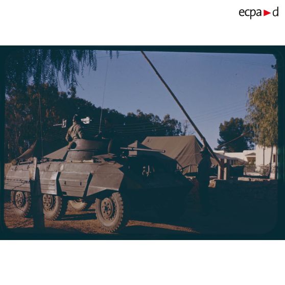 [Une auto-mitrailleuse M8 du 12e régiment de Dragons passe la barrière du camp].