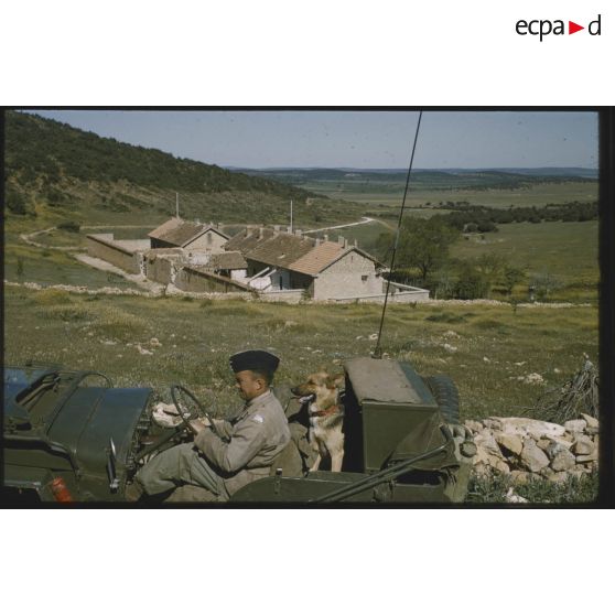 [Opération du 12e RD, une Jeep passe devant des bâtiments endommagés].