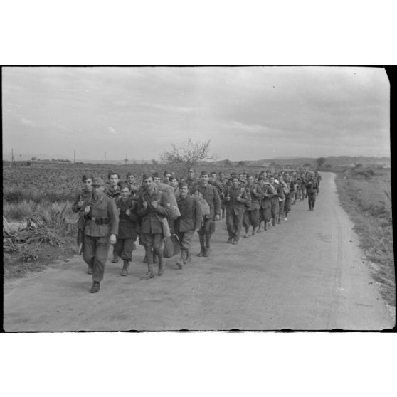 En Crète, dans le secteur de Maleme, une colonne de prisonniers italiens progresse sous la garde d'une sentinelle allemande.