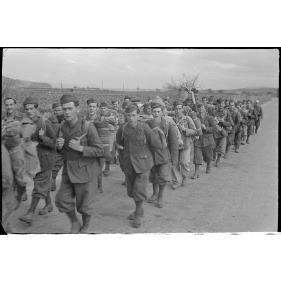 En Crète, dans le secteur de Maleme, une colonne de prisonniers italiens progresse sous la garde d'une sentinelle allemande.