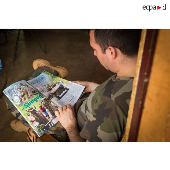Au sein de la plateforme opérationnelle de défense de Bambari, un cadre du commandement du GTIA Turco entame la lecture d'un article du magazine Raid consacré à l'opération Sangaris.