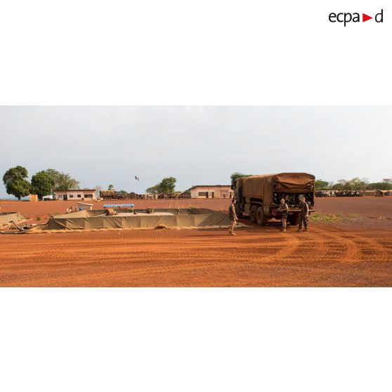 Au sein de la plateforme opérationnelle de défense de Bambari, trois soldats d'une compagnie logistique s'apprêtent à remplir une citerne souple grâce un camion-citerne Scania CCP 10.