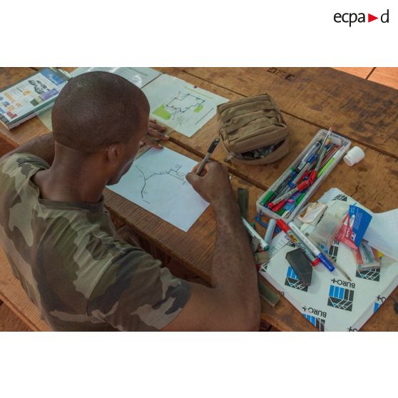 Au sein de la plateforme opérationnelle de défense de Bambari, un soldat prépare l'itinéraire d'une mission à l’aide de cartes et de croquis.