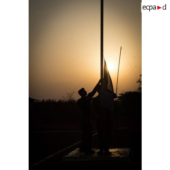 Tirailleurs du GTIA (groupement tactique interarmes) Turco abaissant le drapeau lors de la cérémonie aux couleurs sur la place d'armes de la POD (plateforme opérationnelle défense) de Bambari, au soir du 13 mars 2015.