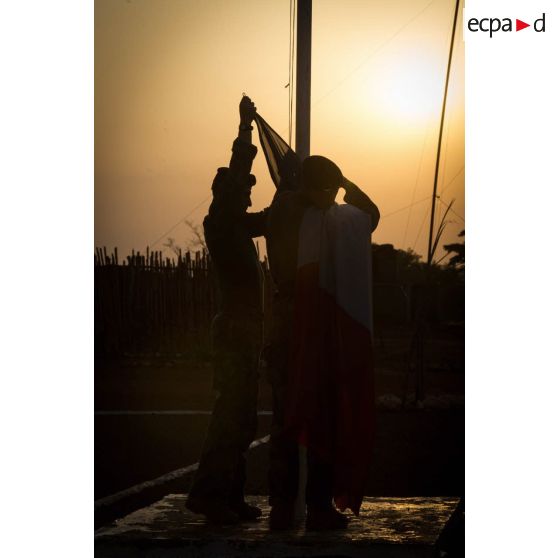 Tirailleurs du GTIA (groupement tactique interarmes) Turco abaissant le drapeau lors de la cérémonie aux couleurs sur la place d'armes de la POD (plateforme opérationnelle défense) de Bambari, au soir du 13 mars 2015.