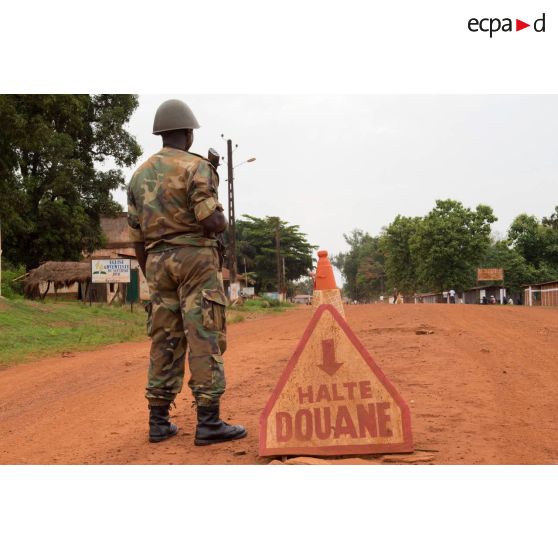 Soldat centrafricain en faction à côté d'un panneau des douanes à Bambari, installé dans le cadre de la réouverture des bureaux douaniers et l'installation dans la ville de l'ORCCPA (office de réglementation, de commercialisation et de conditionnement des produits agricoles).