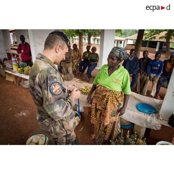 Le colonel Marc Espitalier, chef de corps du 1er RT et commandant le GTIA (groupement tactique interarmes) Turco converse avec une habitante au marché de Bambari, dans le cadre de la réouverture des bureaux douaniers de la ville et l'installation de l'ORCCPA (office de réglementation, de commercialisation et de conditionnement des produits agricoles).