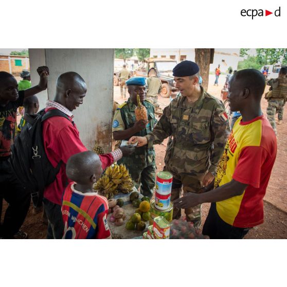 Le colonel Marc Espitalier, chef de corps du 1er RT et commandant le GTIA (groupement tactique interarmes) Turco, accompagné d'un lieutenant-colonel congolais des casques bleus de la MINUSCA (mission multidimensionnelle intégrée des Nations Unis pour la stabilisation en Centrafrique), achète un ananas au marché de Bambari, dans le cadre de la réouverture des bureaux douaniers de la ville et l'installation de l'ORCCPA (office de réglementation, de commercialisation et de conditionnement des produits agricoles).