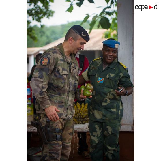 Le colonel Marc Espitalier, chef de corps du 1er RT et commandant le GTIA (groupement tactique interarmes) Turco converse avec un lieutenant-colonel congolais des casques bleus de la MINUSCA (mission multidimensionnelle intégrée des Nations Unis pour la stabilisation en Centrafrique) au marché de Bambari, le fruit de ses achats en main, dans le cadre de la réouverture des bureaux douaniers de la ville et l'installation de l'ORCCPA (office de réglementation, de commercialisation et de conditionnement des produits agricoles).