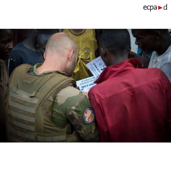 Un sous-officier d'une demi-section du GTIA (groupement tactique interarmes) Turco distribue des tracts à des habitants des alentours lors d'une reconnaissance d'axe entre Bindi et Bambari.