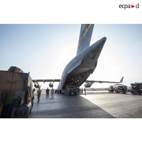 Des éléments du 1er RTP affecté au DéTIA (détachement de transit interarmées) procèdent au chargement de véhicules PVP (petit véhicule protégé) dans la soute d'un avion Douglas C-17 de l'US Air Force stationnant sur le tarmac de l'aéroport M'Poko de Bangui, dans le cadre du désengagement progressif de la force Sangaris.
