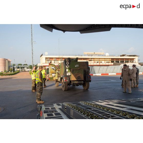 Aidés par le personnel navigant de l'US Air Force, les éléments du 1er RTP affecté au DéTIA (détachement de transit interarmées) procèdent au chargement d'un véhicule PVP (petit véhicule protégé) dans la soute d'un avion Douglas C-17 stationnant sur le tarmac de l'aéroport M'Poko de Bangui, dans le cadre du désengagement progressif de la force Sangaris.