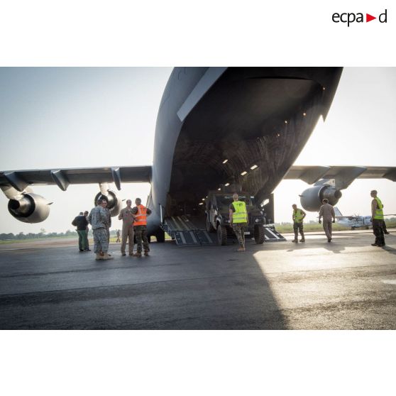Aidés par le personnel navigant de l'US Air Force, les éléments du 1er RTP affecté au DéTIA (détachement de transit interarmées) procèdent au chargement de véhicules PVP (petit véhicule protégé) dans la soute d'un avion Douglas C-17 stationnant sur le tarmac de l'aéroport M'Poko de Bangui, dans le cadre du désengagement progressif de la force Sangaris.