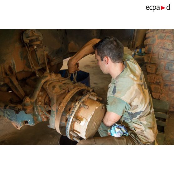 Un mécanicien effectue une réparation sur la roue d'un véhicule, à l'atelier de réparation mécanique du train de combat du camp de M'Poko de Bangui.
