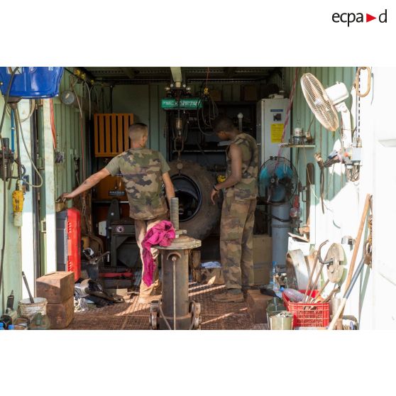 Des mécaniciens effectuent une réparation sur la roue d'un véhicule, à l'atelier de réparation mécanique du train de combat du camp de M'Poko de Bangui.