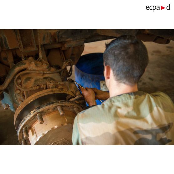 Un mécanicien effectue une réparation sur la roue d'un véhicule, à l'atelier de réparation mécanique du train de combat du camp de M'Poko de Bangui.