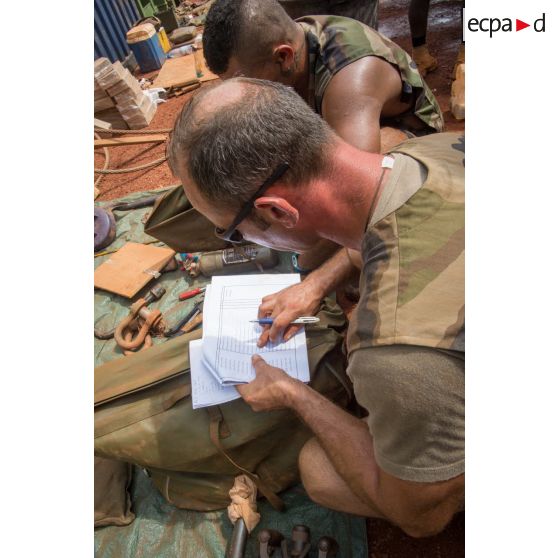 Deux tirailleurs du 1er RT du GTIA (groupement tactique interarmes) Turco procèdent à l'inventaire des outils de réparation dans le cadre d'un reconditionnement de matériel au train de combat du camp M'Poko de Bangui.