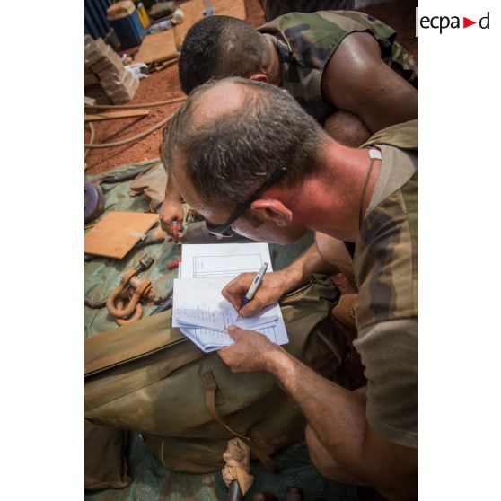 Deux tirailleurs du 1er RT du GTIA (groupement tactique interarmes) Turco procèdent à l'inventaire des outils de réparation dans le cadre d'un reconditionnement de matériel au train de combat du camp M'Poko de Bangui.