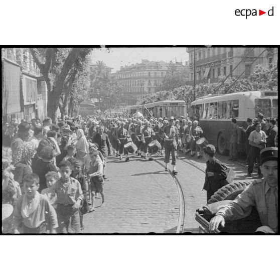 Le 7e régiment de tirailleurs algériens (RTA) et sa musique défilent dans les rues d'Alger, au milieu de la foule.