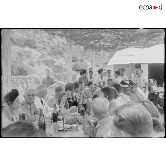 Le général de corps d'armée Henry Martin est attablé avec des personnalités civiles, militaires et des élèves de l'école de vol à voile de Djebel Diss.