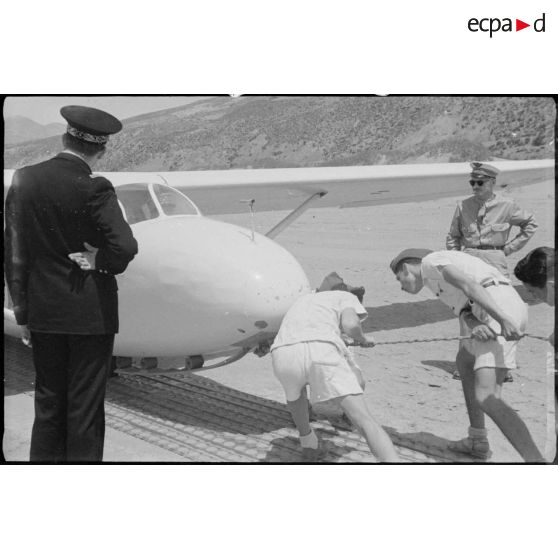 Deux élèves de l'école de vol à voile de Djebel Diss préparent le vol d'un planeur sous le regard de deux autorités militaires.