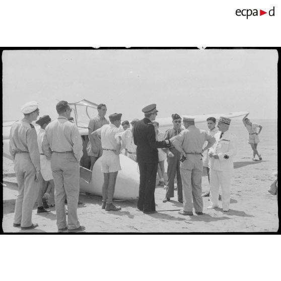 Photographie de groupe rassemblant le général de corps d'armée Henry Martin, des personnalités militaires, des personnalités civiles et des élèves de l'école de vol à voile de Djebel Diss, devant un planeur.