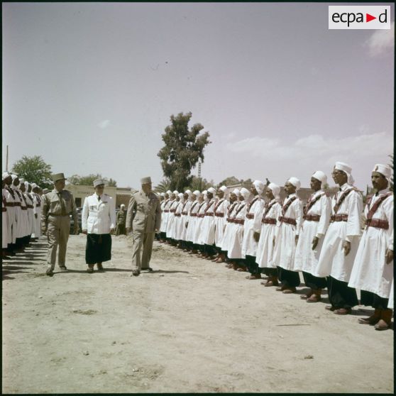 Prise d'armes d'une compagnie portée saharienne, dans une ville algérienne traditionnelle située dans le désert saharien.