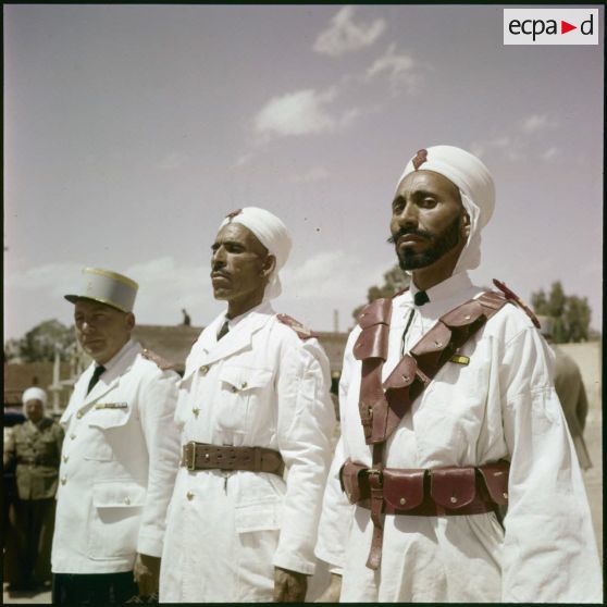 Prise d'armes d'une compagnie portée saharienne, dans une ville algérienne traditionnelle située dans le désert saharien.