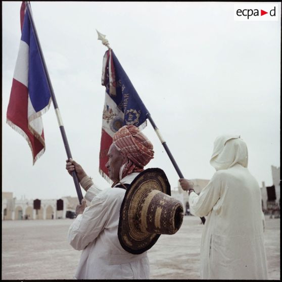Portrait d'un ancien combattant tenant un drapeau, pour la visite de Max Lejeune dans le sud oranais.