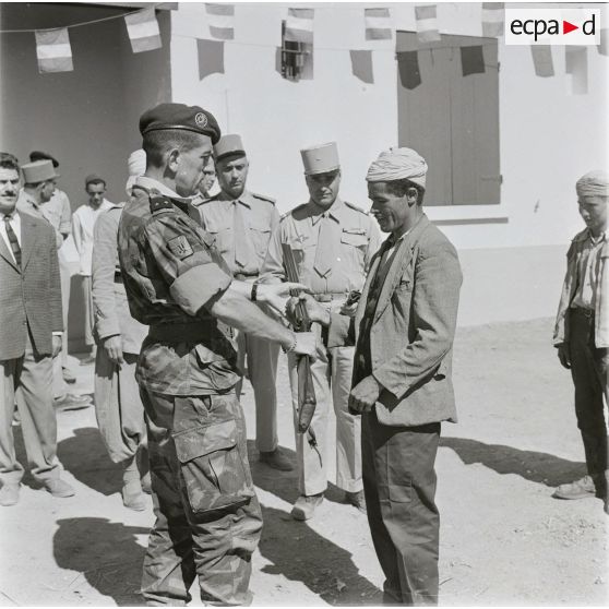 [Le général de brigade Jacques Massu remet un fusil à un Algérien, 1956-1958.]