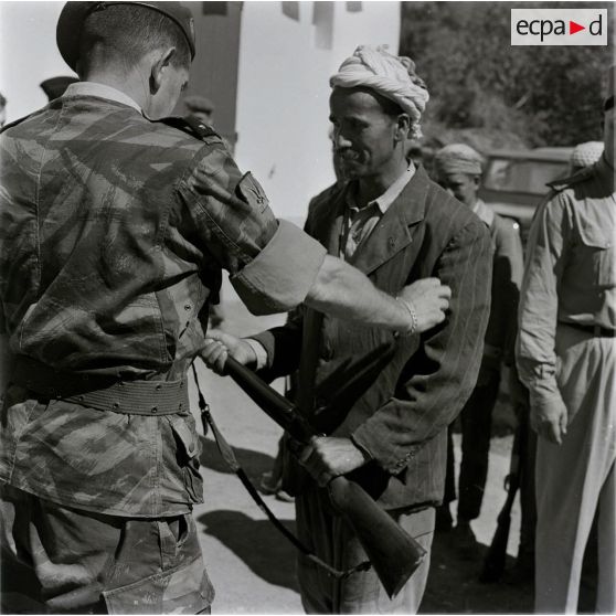 [Le général de brigade Jacques Massu remet un fusil à un Algérien, 1956-1958.]