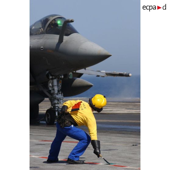 Sur le porte-avions Charles de Gaulle, un équipier de pont d’envol (chien jaune) donne le vert pour le catapultage d’un Rafale.