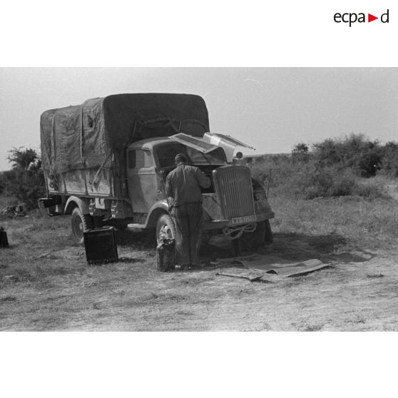 Un soldat travaille sur le moteur d'un camion Opel Blitz immatriculé WH 935 505 du Pz.Art.Rgt-155 de la 21-Pz.Div.